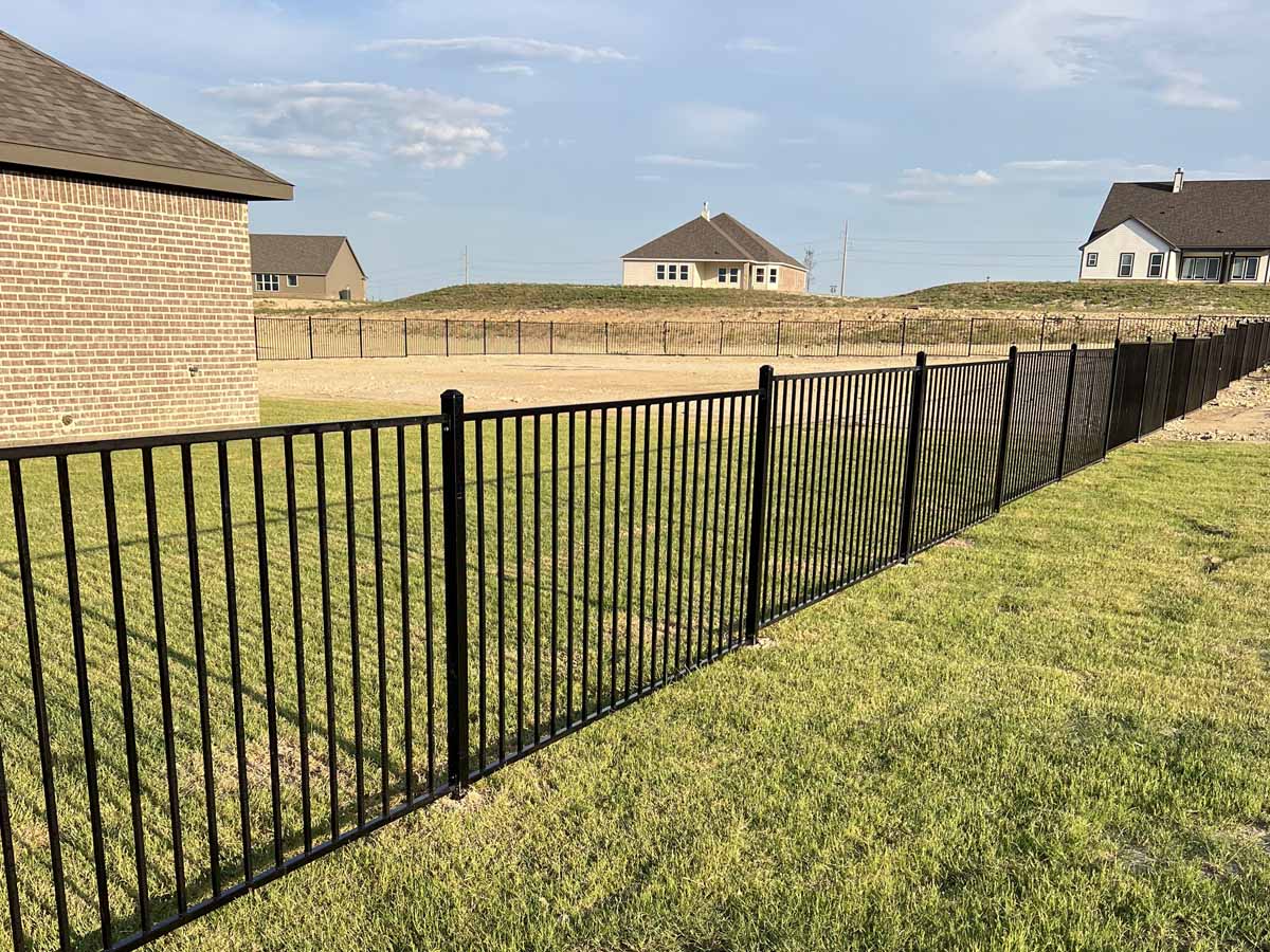 Fence with Black Aluminum Fence Surrounding Backyard of Brick Home in Fort Worth, Texas Suburb in Fort Worth, TX