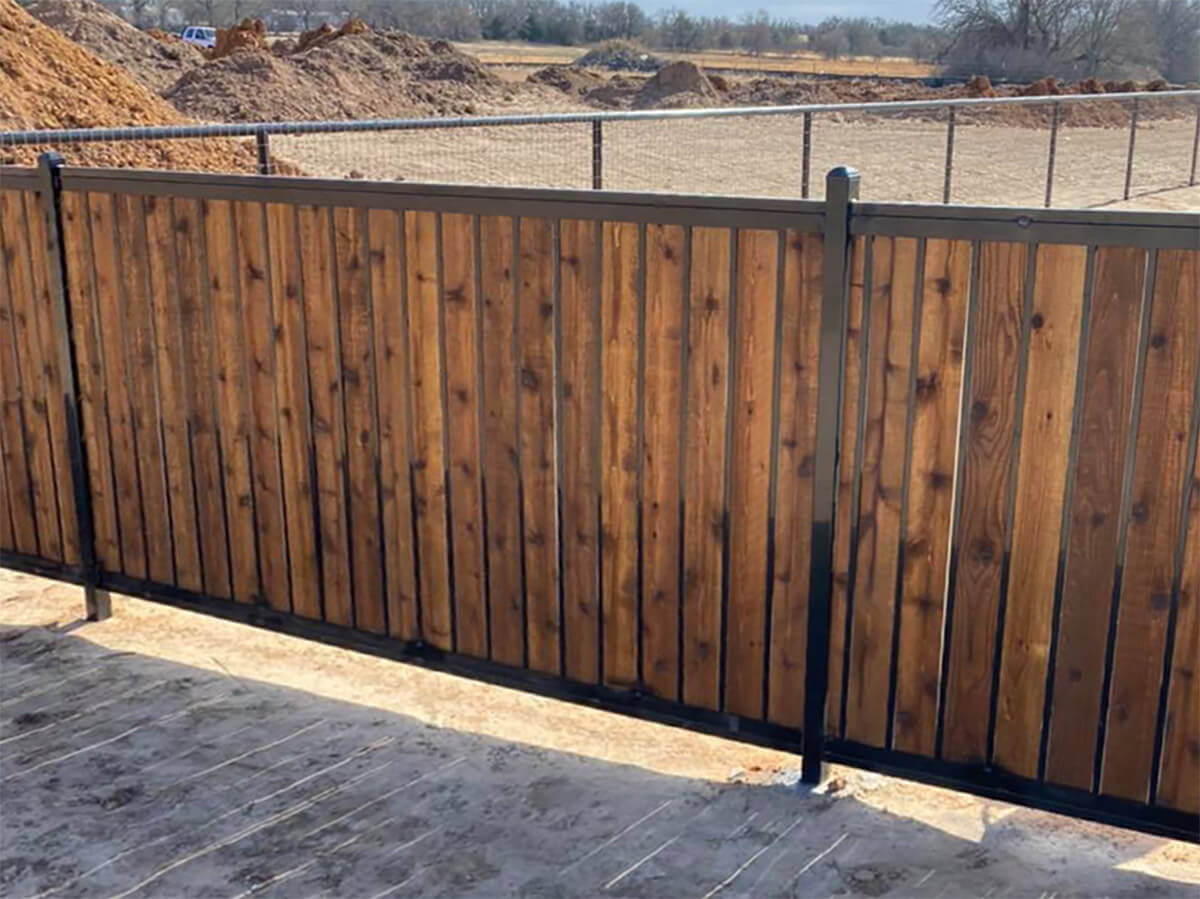 Fence with Wood fence with metal frame and posts installed around a dirt field in Fort Worth TX in Fort Worth, TX