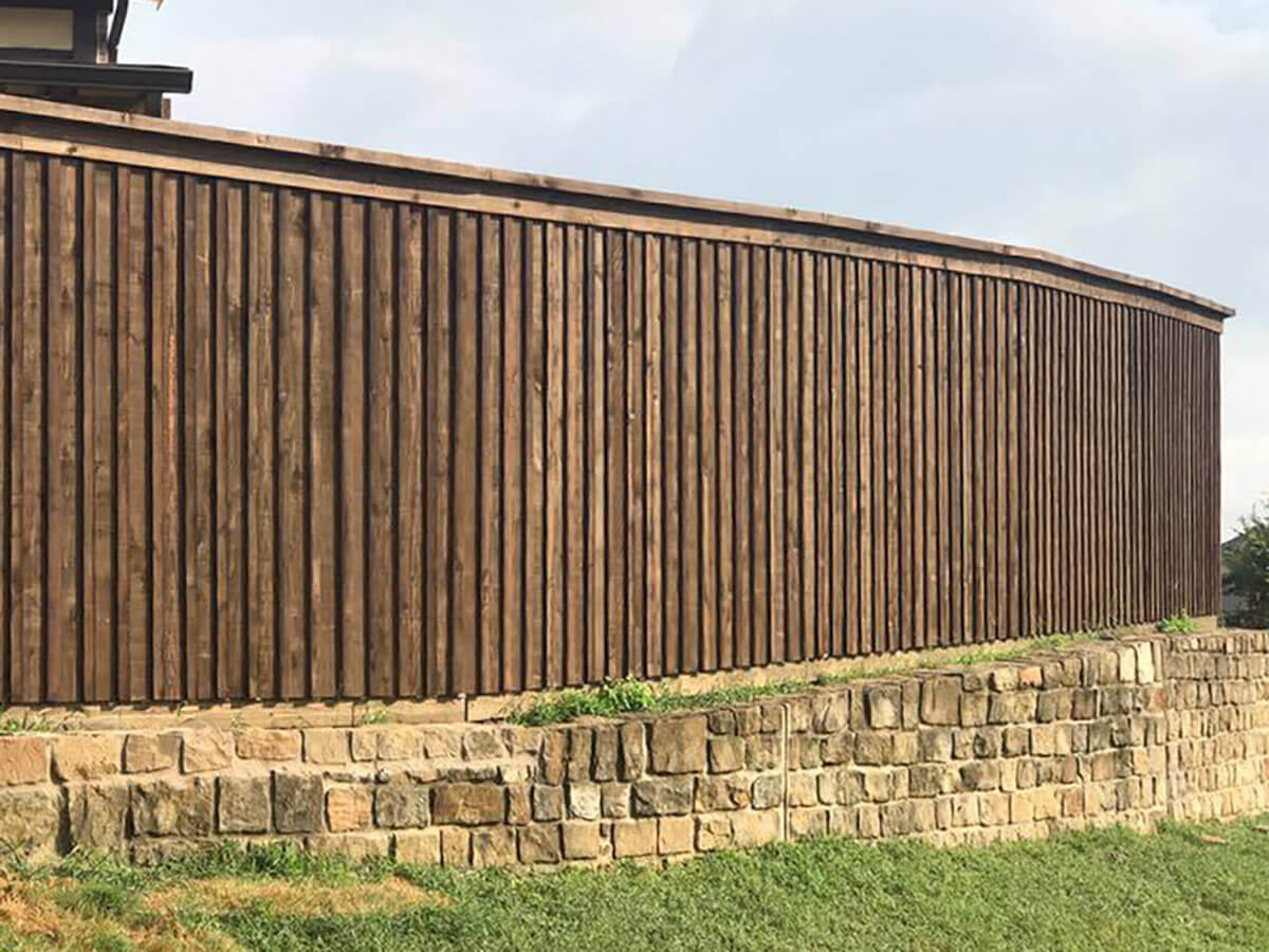 Fence with Board on board wood fence with cap and trim installed on a stone wall in Fort Worth TX in Fort Worth, TX